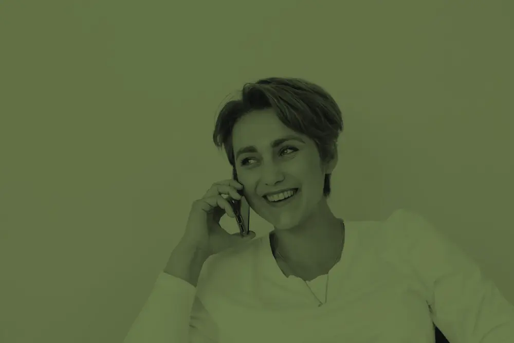 Una clienta sonríe mientras habla por teléfono para pedir cita